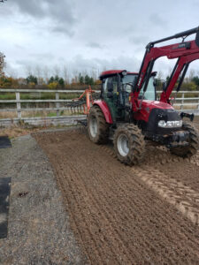Red Tractor with front loader in a muddy field.
