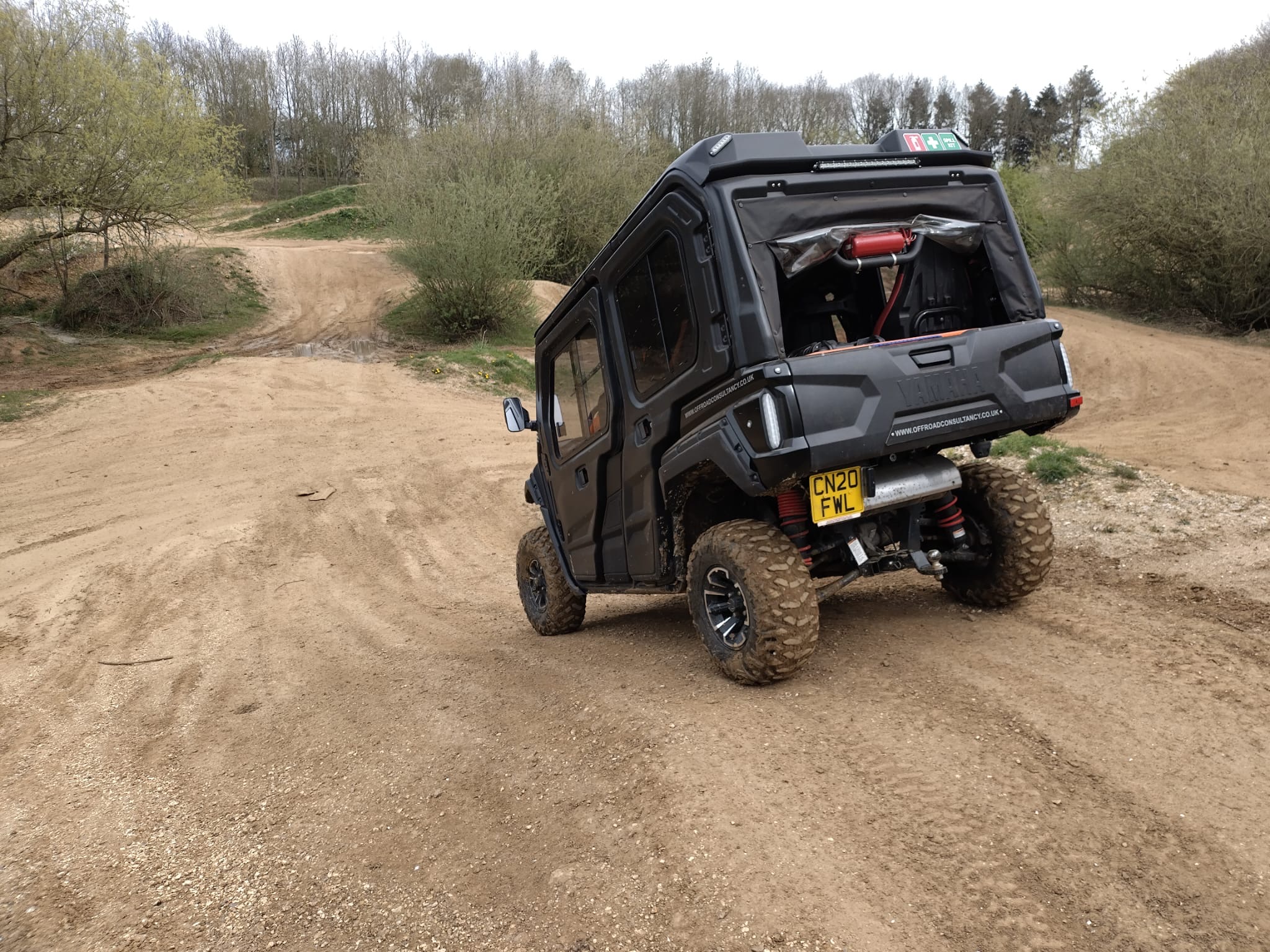 A black Side by Side ATV driving down a slope in a quarry.